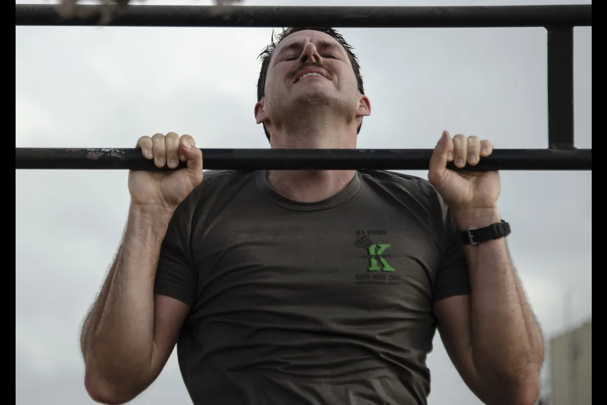 A man at the top of a pull-up with his chin above the bar, the position a negative starts from